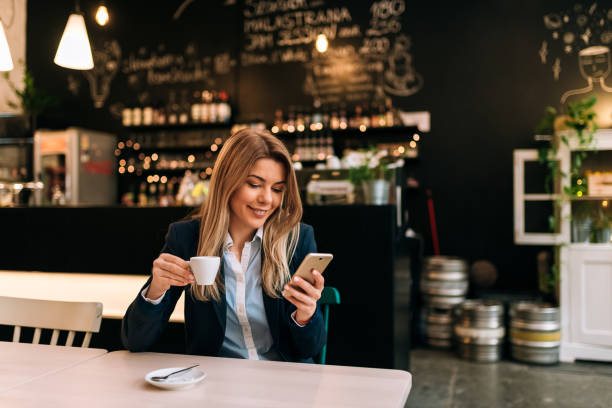 istock Charming woman using phone while holding a cup of coffee. 943494920