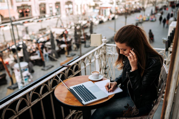 istock Young female entrepreneur working outdoors. Writting in a notebook while talking on a phone. 943494946