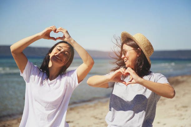 Happy beautiful womans standing on beach with friend laughing stock photo