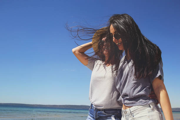 Young female friends walking on beach in summer