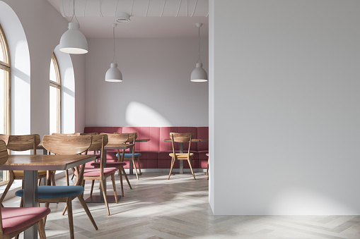 Stylish bar interior with white walls, a concrete floor, original windows, dark pink sofas, round tables and chairs. A blank wall fragment. 3d rendering mock up