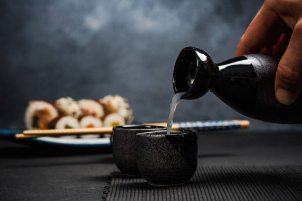 Man pouring sake into sipping bowl stock photo