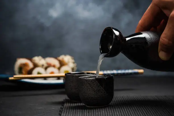 Man pouring sake into sipping bowl.