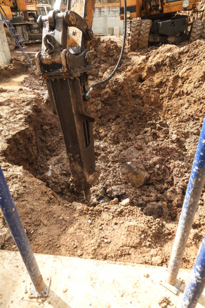 istock Excavator with a jackhammer breaks rocks in the ground 943515576