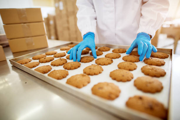 nahaufnahme der frisch gebackene kekse auf weißblech inspizierten vom arbeitnehmer mit sterilen tüchern. - close up cookie gourmet food stock-fotos und bilder