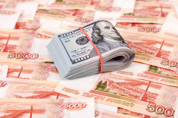 istock Folded dollar bills wrapped by rubber band over banknotes of russian rubles 943528186