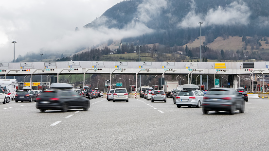 Many cars approaching toll gate on highway, mountain scenery