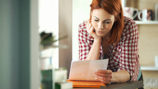 High Cost of Living Closeup of attractive mid 30's housewife looking at monthly bills that seem to have skyrocketed. filling out stock pictures, royalty-free photos & images