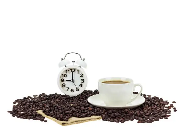 Cofee seed brown color on white background with the clock white color and coffee cup, it's the coffee time for morning day.