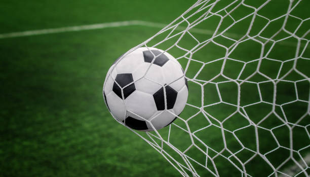 istock Soccer ball on goal with net and green background 943584724