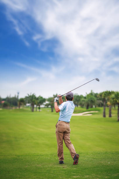 joueur de golf asiatique sur tee off vert après swing - golf playing teeing off men photos et images de collection