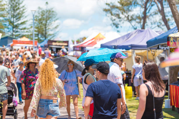 People shopping at festival stall on outdoor fair in Byron Bay, NSW, Australia Byron Bay, NSW, Australia- January 3, 2018: Group of people singing and dancing on the streets in Byron Bay, a paradise with gorgeous beaches and coastal trails on the North Coast of NSW, Australia. byron bay stock pictures, royalty-free photos & images