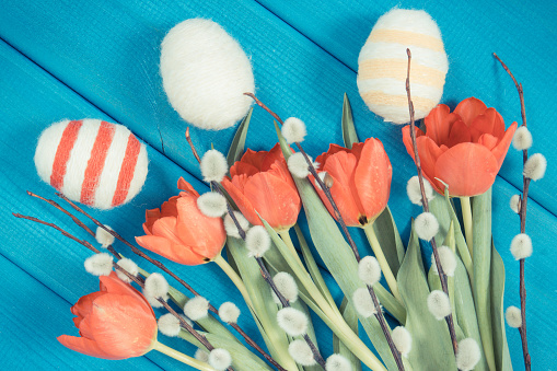 Foto de época, tulipanes rojos, amentos de Pascua y los huevos envuelven cadena de lana, decoración festiva photo