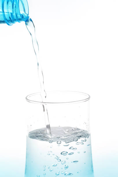 istock Pouring water from bottle into glass on white background. 943602008