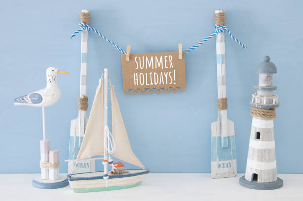 istock nautical concept with wooden decorative boat oars and hanging note message on a string next to lighthouse, seagull and boat over blue background. 943602658
