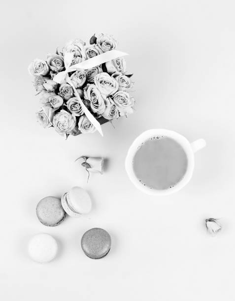 Macaroons with bouquet of roses and cup of coffee. black and white. top view.copy space