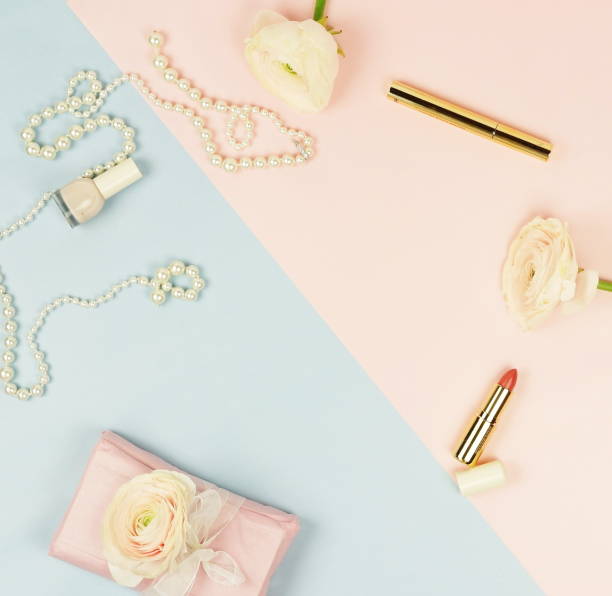 ピンクのラナンキュラスの花、プレゼント ボックス、化粧品、ブルーの淡いピンクの背景に真珠のネックレス。トップの view.copy スペース