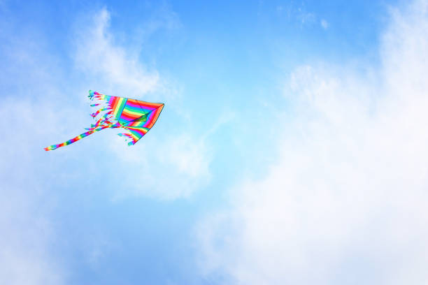 istock Colorful kite flying in the blue sky through the clouds 943610182