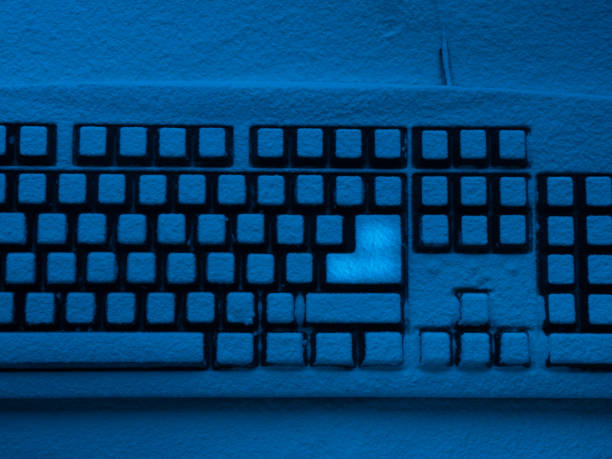 istock PC computer keyboard covered with snow illuminated with blue neon light and brightly lit enter button 943612948