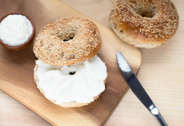 istock Bagel sesame with spread cream cheese close-up on a wooden cut board. 943620946