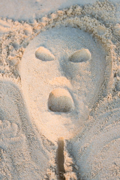 Screaming face of alien, sand art on the beach