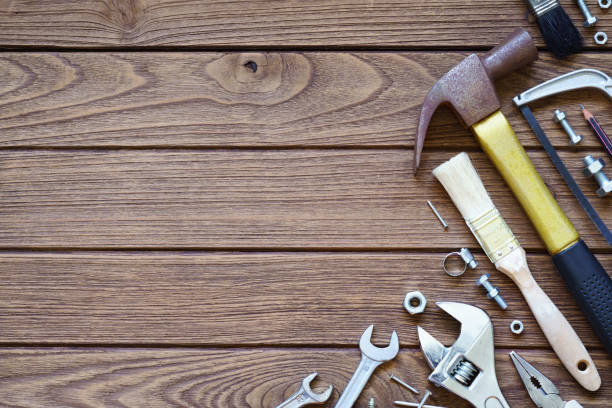 istock Varieties handy tools on wooden background. Hammer, saw, wrenches, adjustable wrench, paint brushes, nail, nuts and bolts on wooden background. Top view with copy space. 943631452