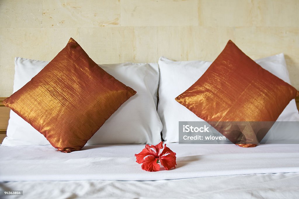 Made up bed with four pillows and one flower  Bed - Furniture Stock Photo