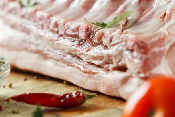 Background meat. Close up - raw meat of pork on a blue background with a pepper and spices