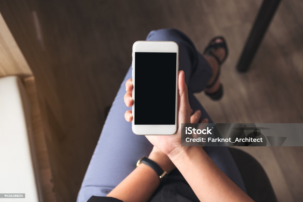 Draufsicht Mock-up Bild einer Frau mit weißen Handy mit leeren schwarzen Desktop-Bildschirm am Oberschenkel im café - Lizenzfrei Handy Stock-Foto