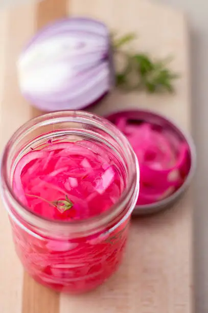 Pickled red onions condiment. Pickling red onions is easy, simply marinate the onions in a brine with vinegar, salt and herbs. Pickled food can be preserved in glass jar for a very long time!