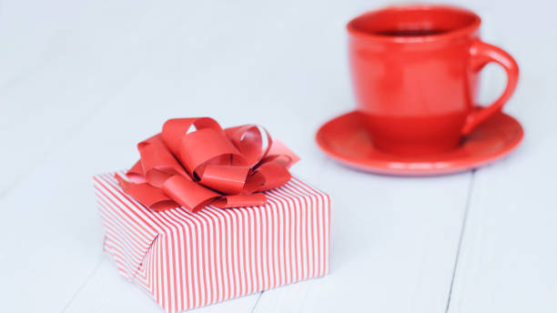 istock close-up background image of red Cup and gift box on light background. 943646318