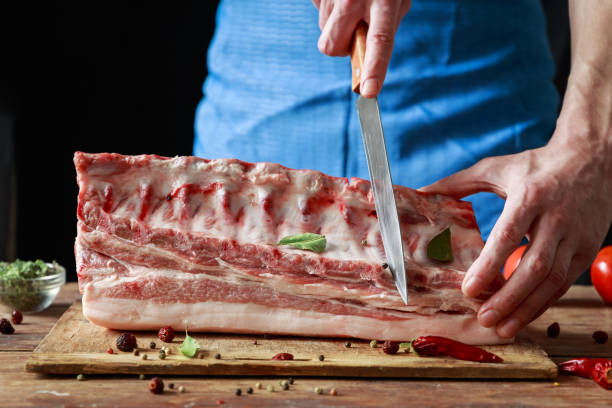 istock Chef cutting meat on a wooden table. Copy space 943649514