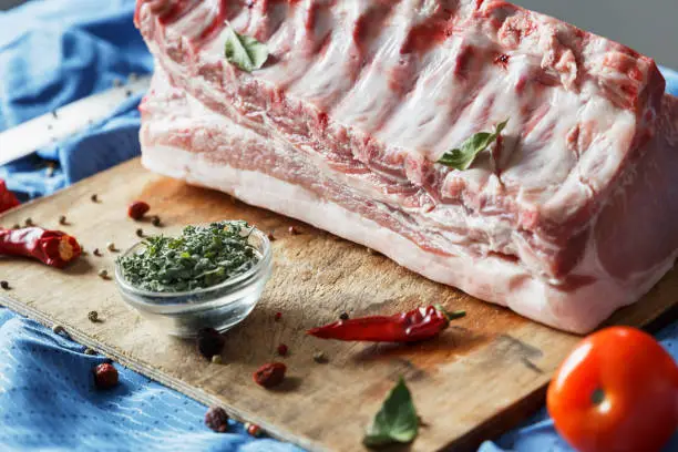 Raw meat of pork on a blue background with a knife and spices