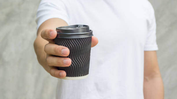 Men holding a cup of coffee on gray background.