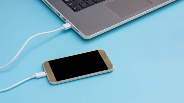 istock Smartphone connecting to a laptop on a blue background. 943662762