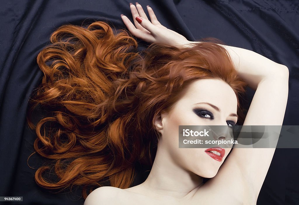 Red haired woman looking at camera seductively laying down Beautiful sexy woman with red hair Adult Stock Photo