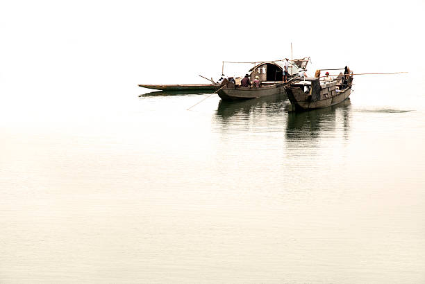 A compact white and blue fishing boat floats quietly on rippling harbor water, casting a soft reflection on the surface.