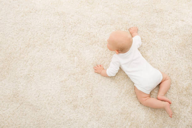 bebé gateando en alfombra fondo, vista superior del niño, niño recién nacido en manta color beige - acostado boca abajo fotografías e imágenes de stock