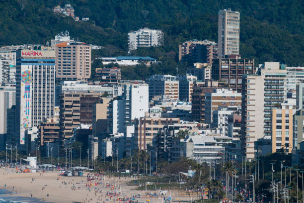 Holidaymakers on the beach in Ipanema. Many are visible and identifiable as they soak up the sun at the water's edge