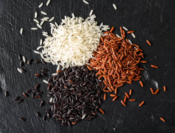 Set of various rice isolated on black background: black, basmati, and red mixed rice. Top view.