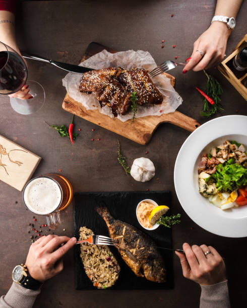 Top view of a couple in love having dinner in a restaurant, fried fish with rice, beer, lettuce, fried ribs, wine