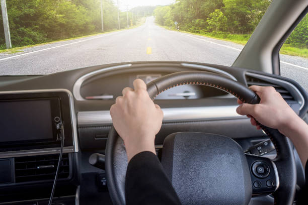 istock Hand holding right steering wheel with highway in rural 943710154
