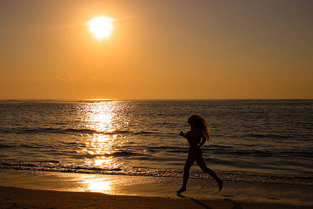 istock Female running along the beach at sunrise 94371083