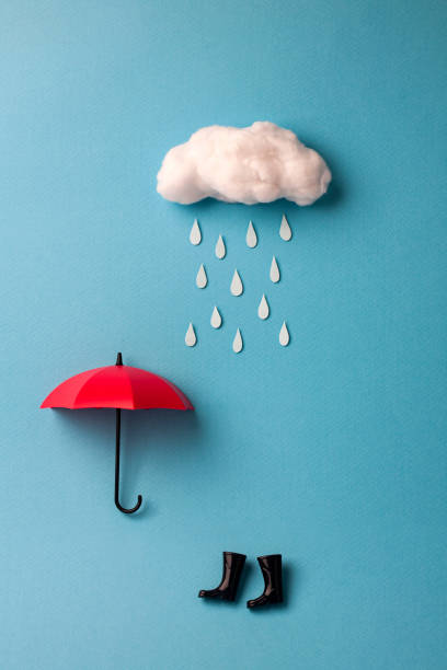 istock umbrella and rain boots under the cloud on sky blue background 943718902