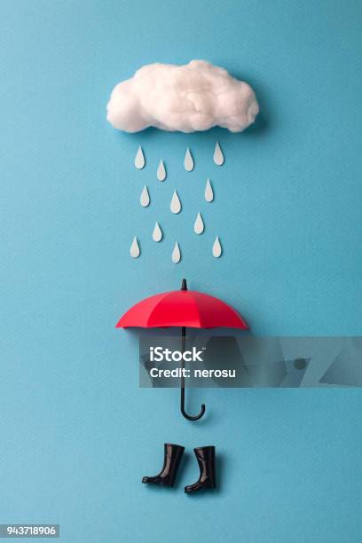 Umbrella And Rain Boots Under The Cloud On Sky Blue Background Stock Photo - Download Image Now