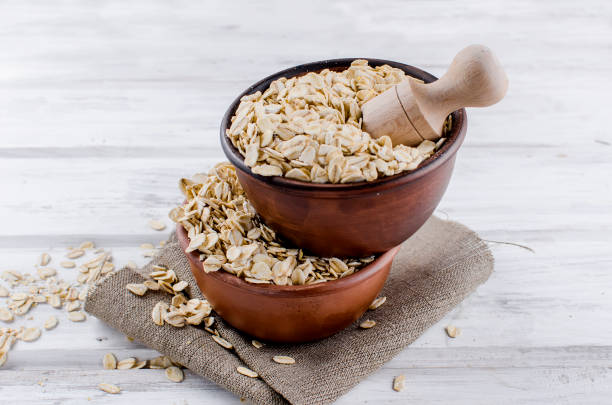 istock Oat flakes  in ceramic bowl and wooden spoon 943721406