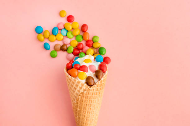 istock Ice cream in a waffle cone with colored candy toppings on a pink background 943721894