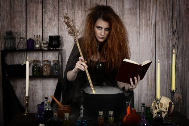 witch in her cottage making a magic potion witch in her cottage making a magic potion holding her spell book witch photos stock pictures, royalty-free photos & images
