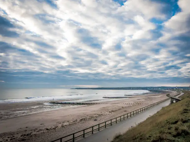 A dramatic sky stretches over Aberdeen Beach in Scotland, UK as the light for the day begins to fade.  This long stretch of pristine beach is deserted as the North Sea gently laps the shore line.