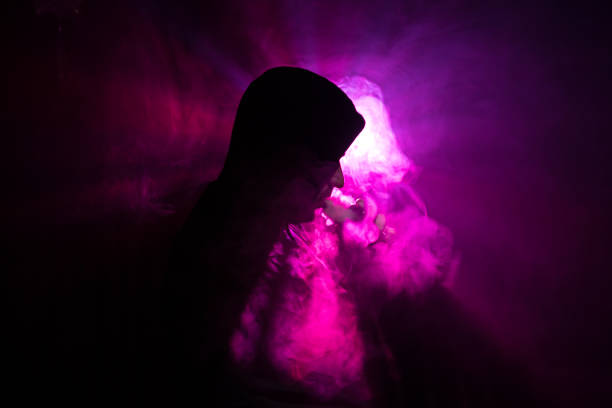 istock Vaping man holding a mod. A cloud of vapor. Black background. Vaping an electronic cigarette with a lot of smoke. Vape concept 943729666
